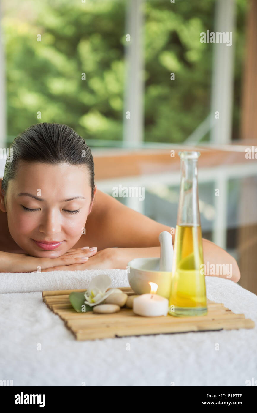 Brunette lying on massage table with tray of beauty treatments Stock Photo