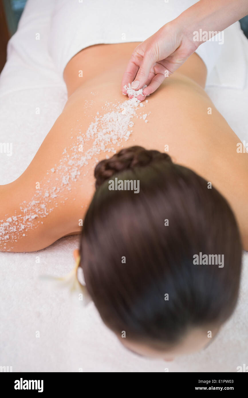 Beauty therapist pouring salt scrub on womans back Stock Photo