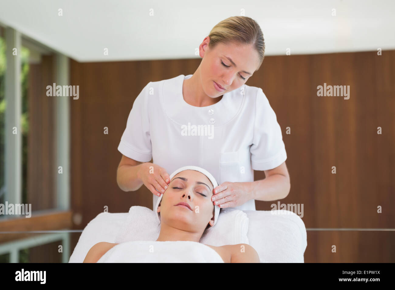 Peaceful brunette getting facial massage from beauty therapist Stock Photo