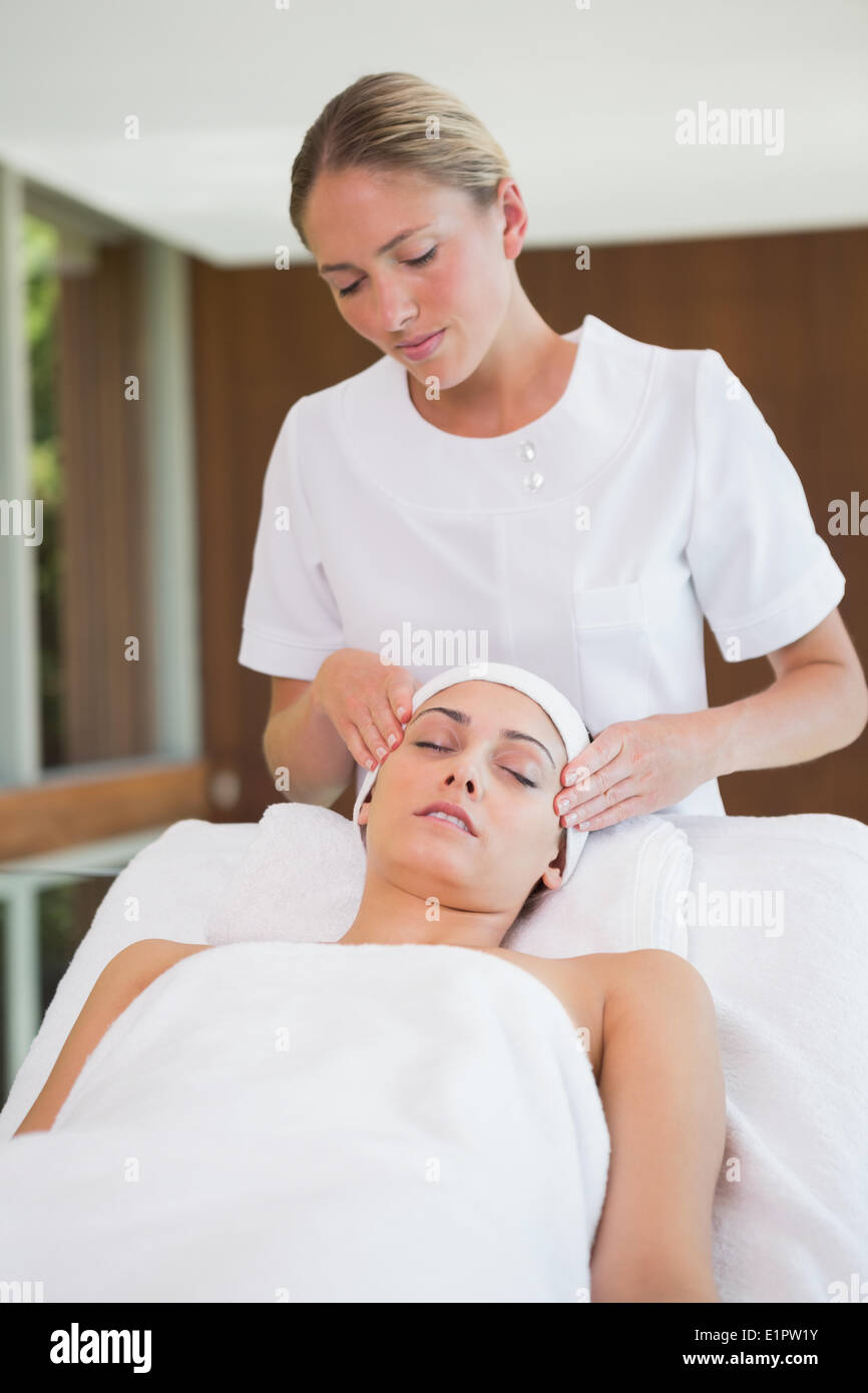 Peaceful brunette getting facial massage from beauty therapist Stock Photo