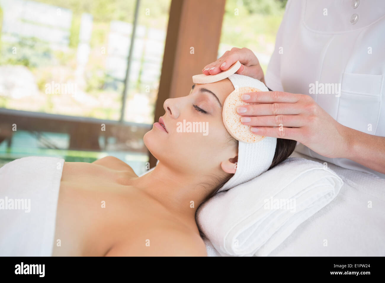 Peaceful brunette getting facial from beauty therapist Stock Photo