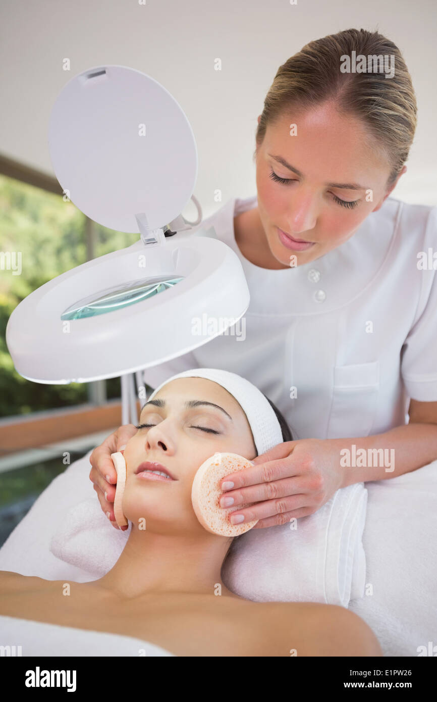 Peaceful brunette getting facial from beauty therapist Stock Photo