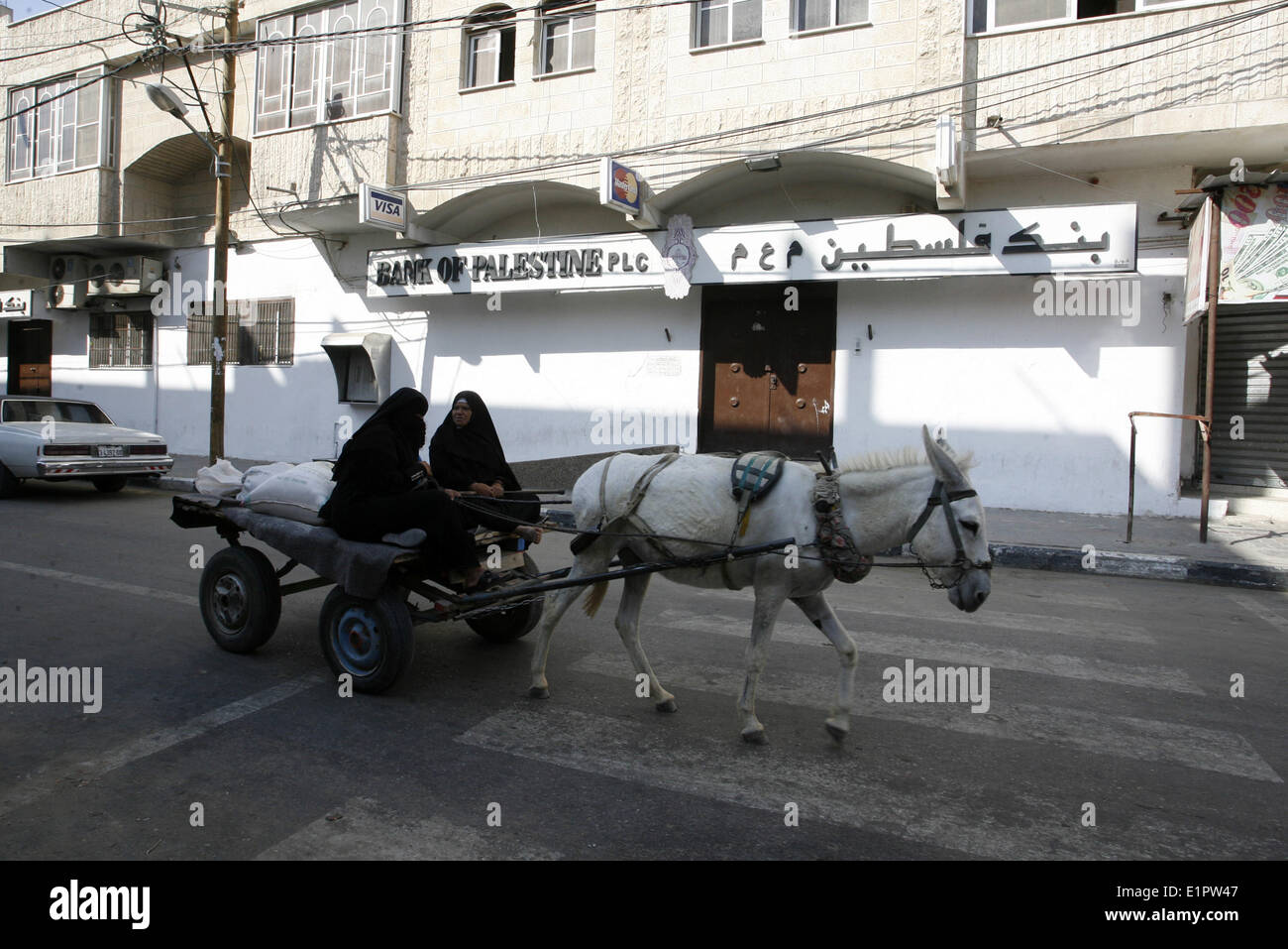 Gaza, Gaza Strip, Palestinian Territories. 8th June, 2014. Palestinian women riding on a donkey cart a walks next to the Palestine Bank after shut by the staff of the Hamas government in Rafah in the southern Gaza Strip on June 8, 2014. A Hamas officials shut banks after the rejection of President Mahmoud Abbas in a meeting through an Egyptian TV yesterday evening to receive their wages after the reconciliation agreement and the Government of National Unity in the past month. © Abed Rahim Khatib/NurPhoto/ZUMAPRESS.com/Alamy Live News Stock Photo