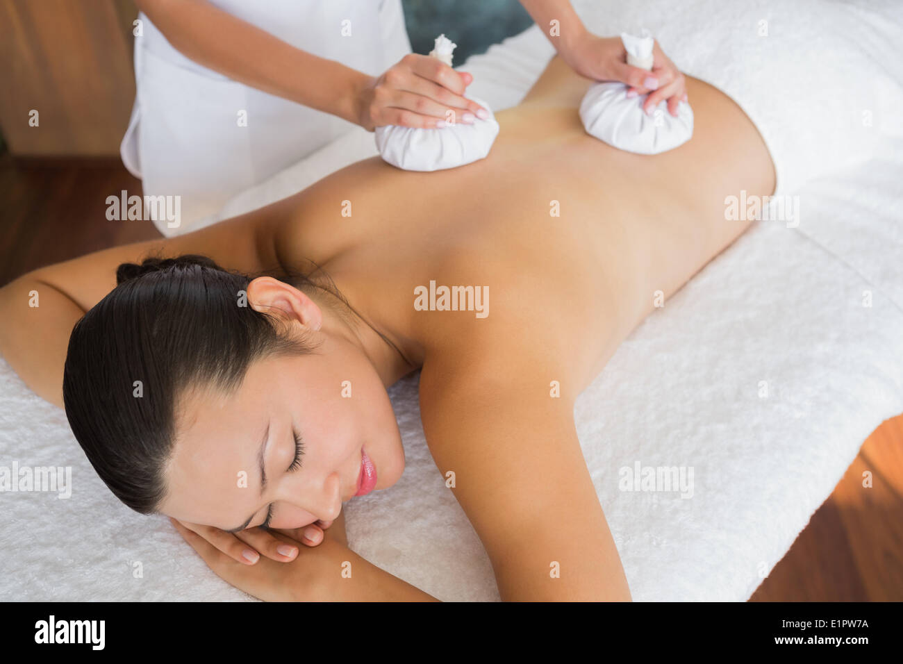 Content brunette getting a herbal compress massage Stock Photo