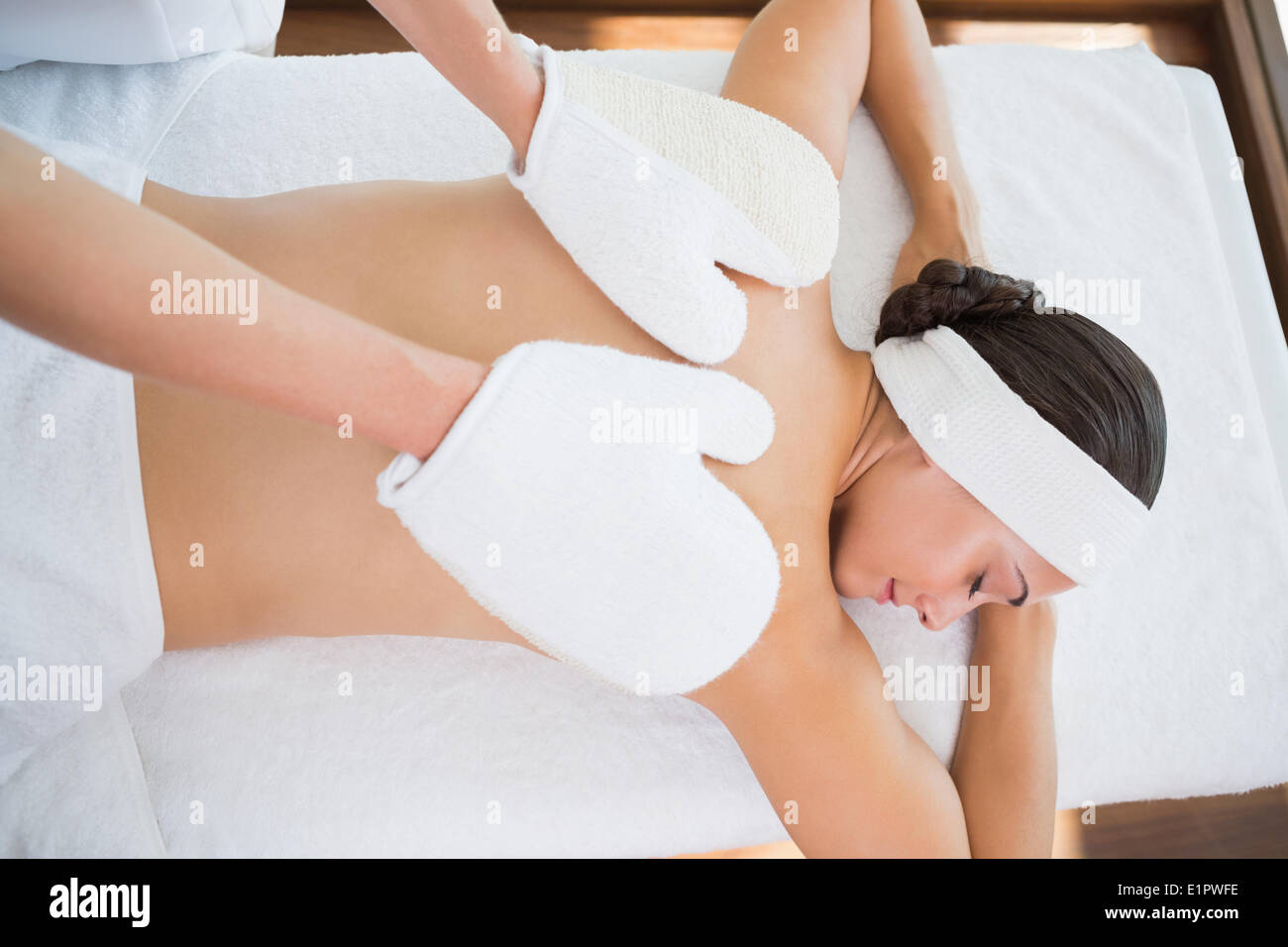Beauty therapist rubbing womans back with heated mitts Stock Photo