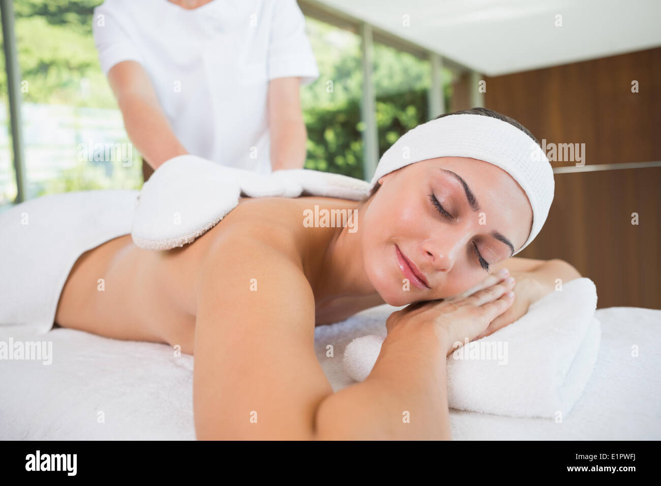 Beauty therapist rubbing smiling womans back with heated mitts Stock Photo