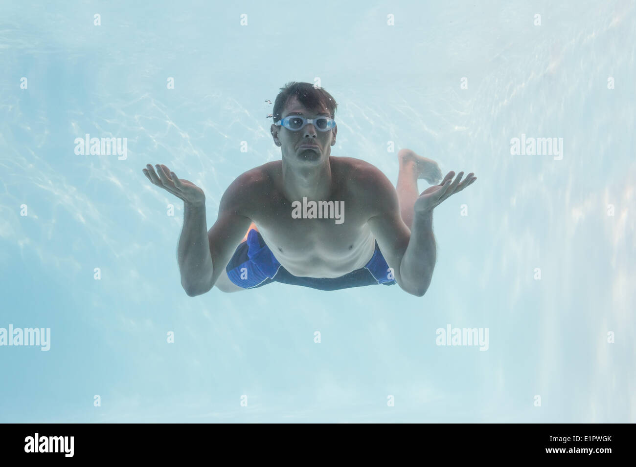 Man shrugging shoulders underwater in swimming pool Stock Photo