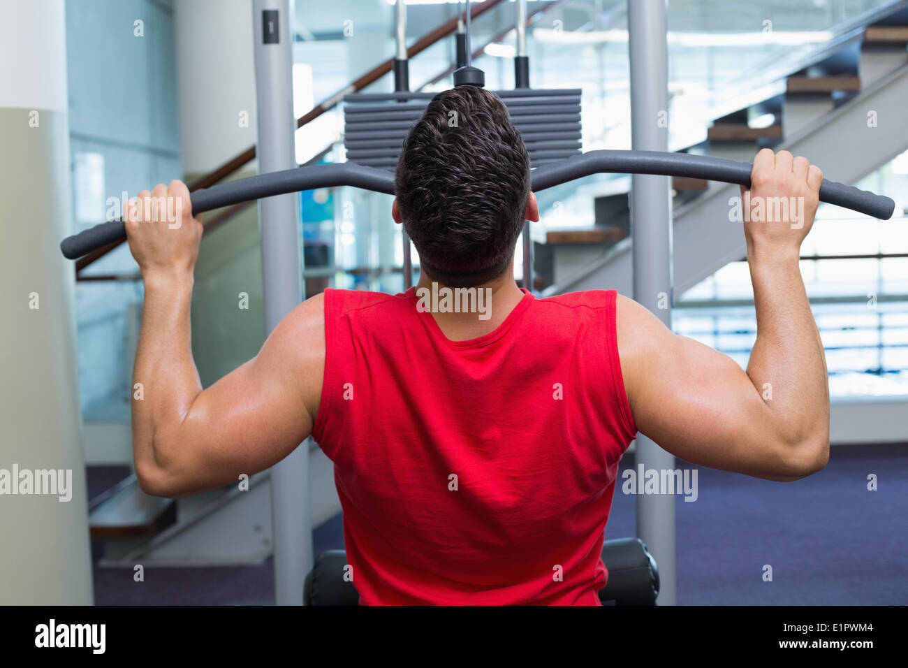 Strong bodybuilder using weight machine for arms Stock Photo Alamy