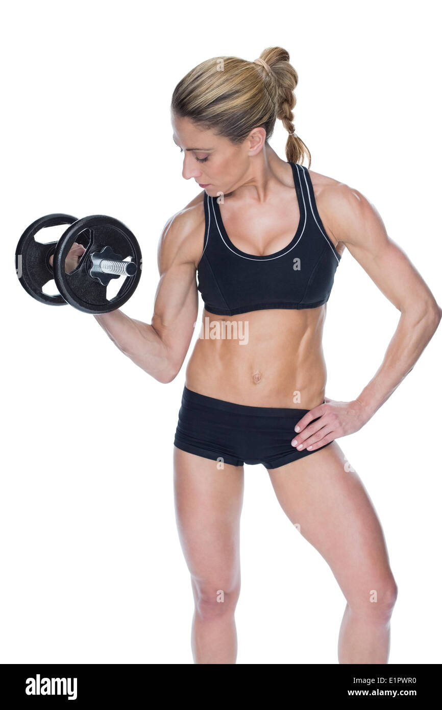 Female bodybuilder holding large black dumbbell with arm up looking at bicep Stock Photo