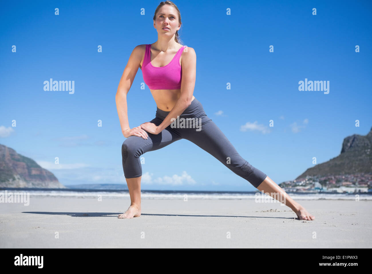 Focused fit blonde warming up on the beach Stock Photo