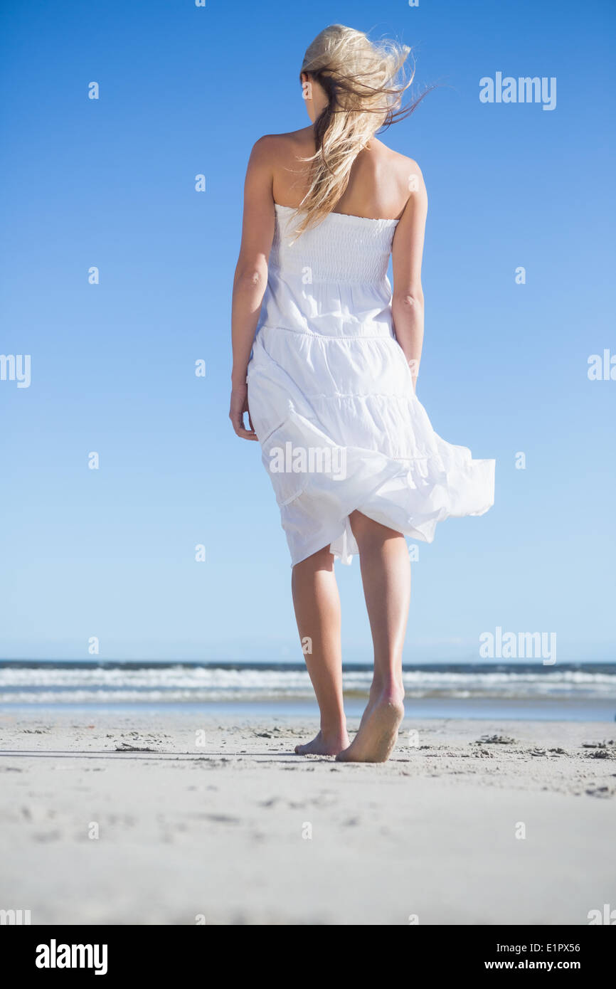 Blonde in white dress strolling on the beach Stock Photo