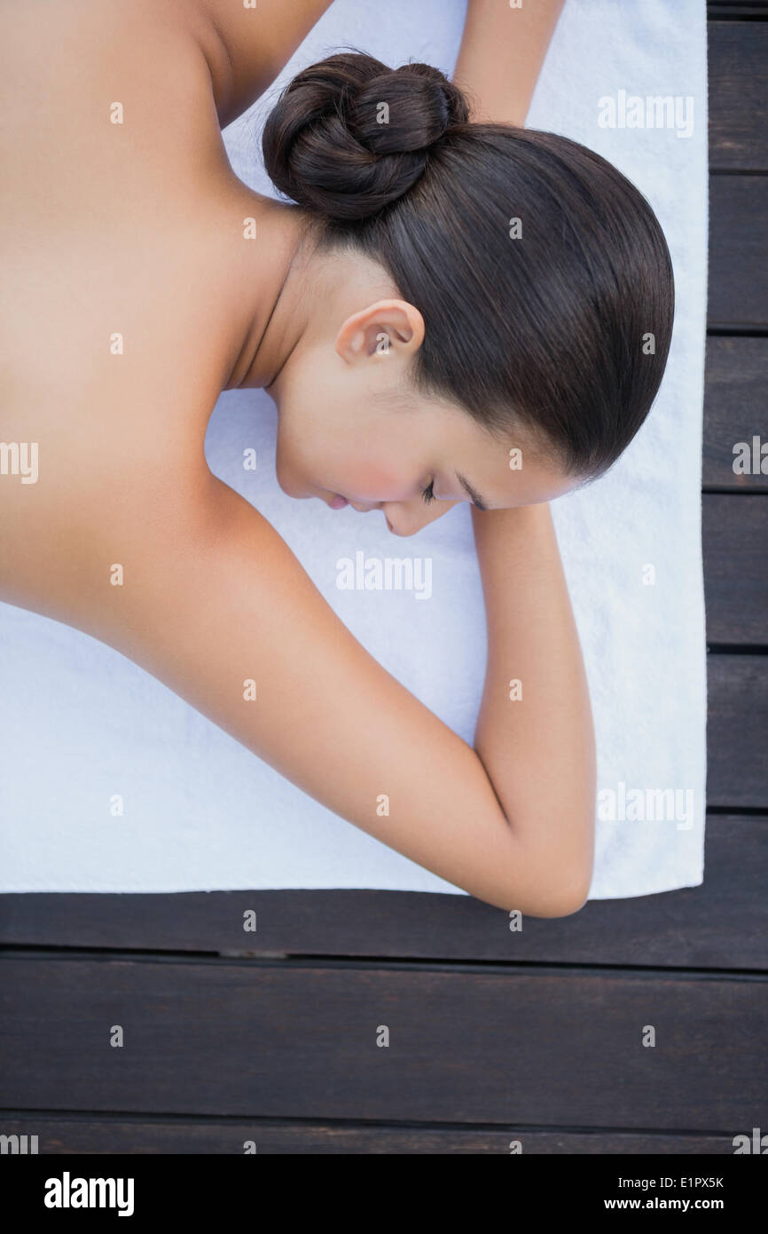 Peaceful brunette lying poolside on towel Stock Photo