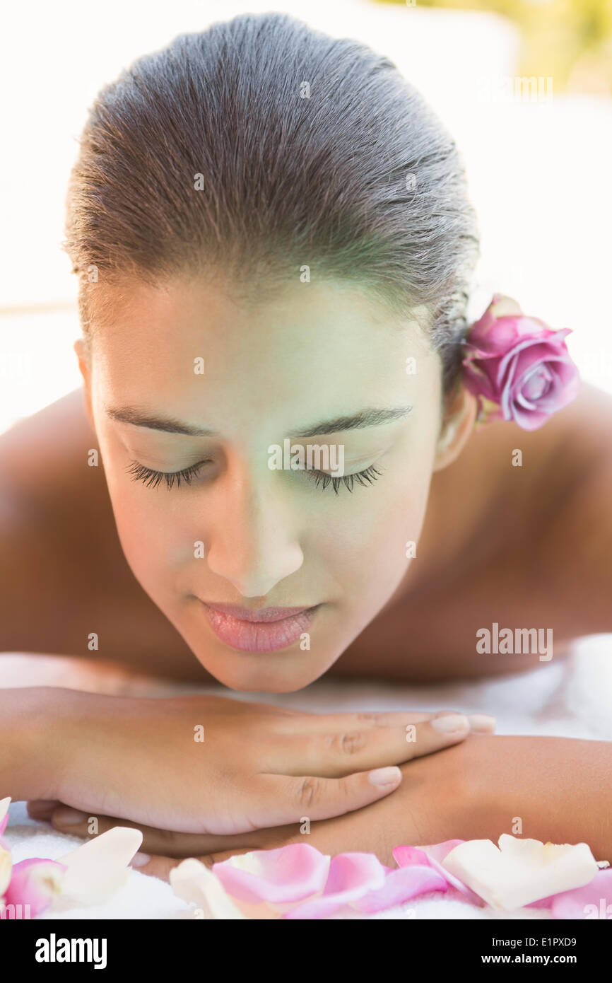 Calm brunette lying on towel with rose petals Stock Photo
