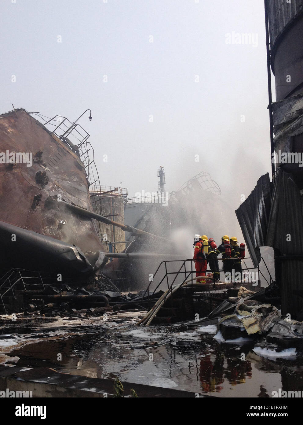 Nanjing, China's Jiangsu Province. 9th June, 2014. Photo taken with a mobile phone shows firemen putting out fire at the accident site after an explosion ripped through the refinery of Sinopec Yangzi Petrochemical Co. in Nanjing, capital of east China's Jiangsu Province, June 9, 2014. Crude oil tanks near the sulfur recovery facility at the refinery exploded Monday noon, and three of eight oil tanks at the site were on fire after the explosion toppled them down. It was not immediately known whether the blast and fire have caused casualties. Credit:  Wang Wei/Xinhua/Alamy Live News Stock Photo