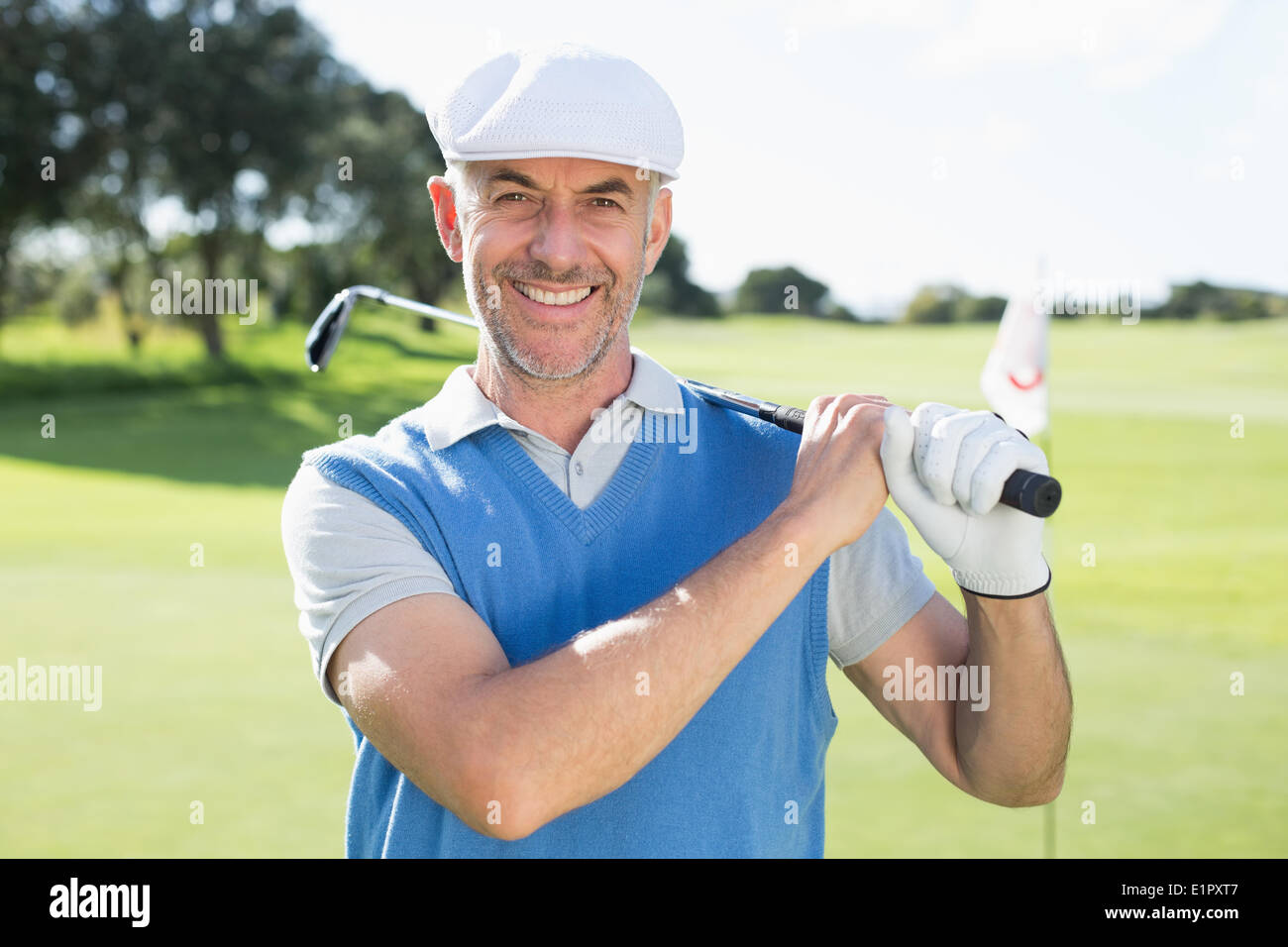 Golfer standing and swinging his club smiling at camera Stock Photo - Alamy