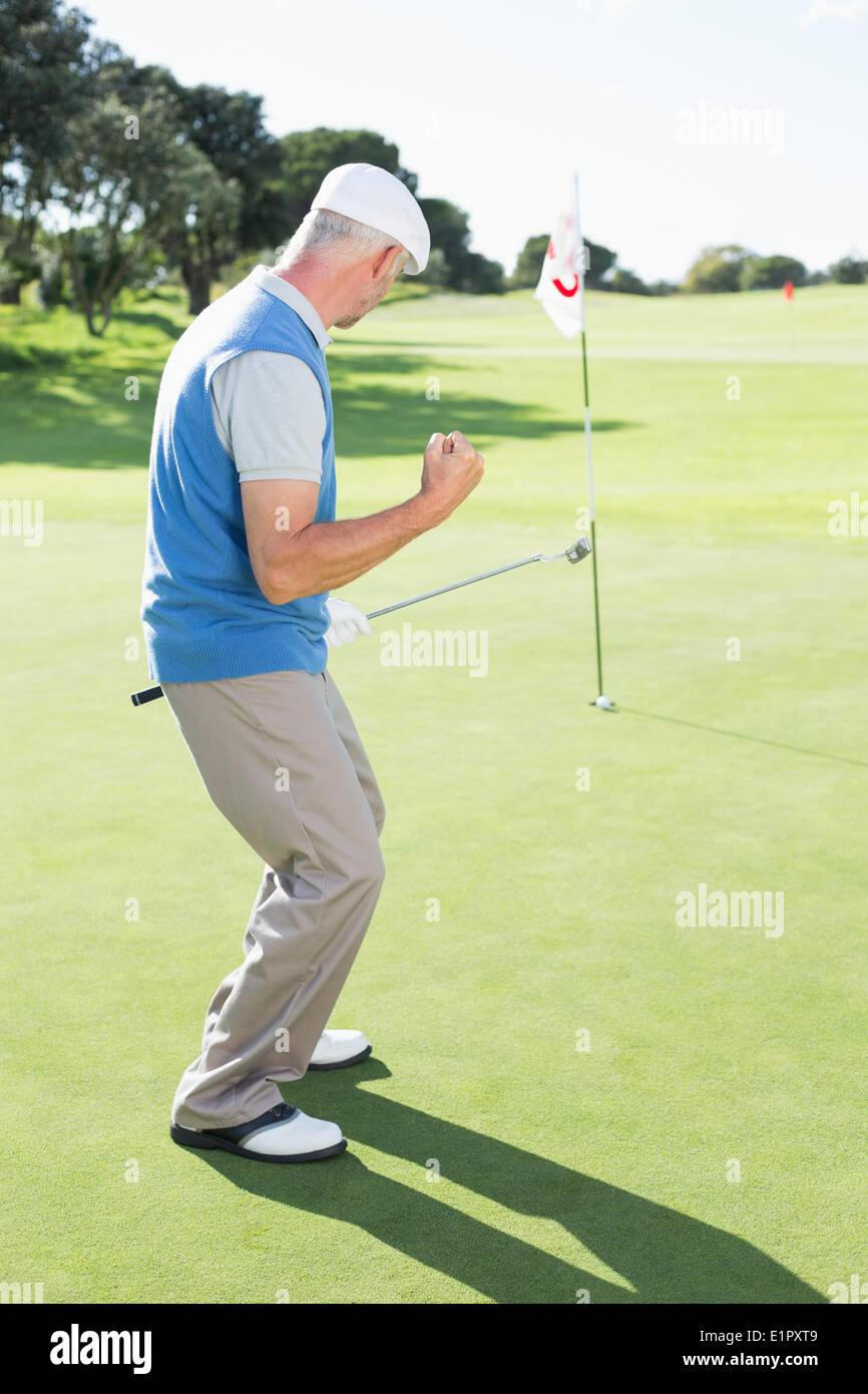 Happy golfer cheering on putting green at eighteenth hole Stock Photo