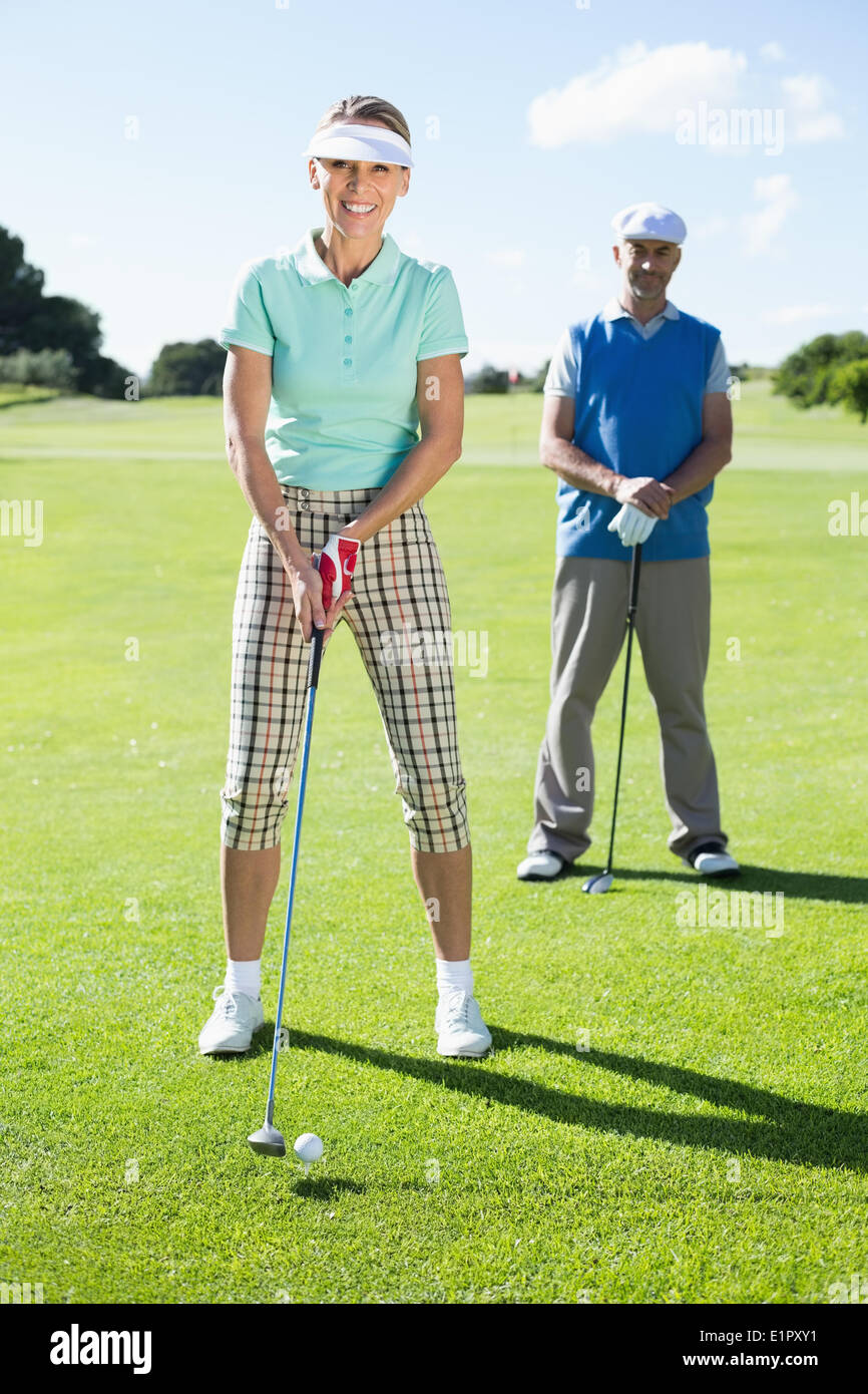 Smiling lady golfer teeing off for the day watched by partner Stock Photo