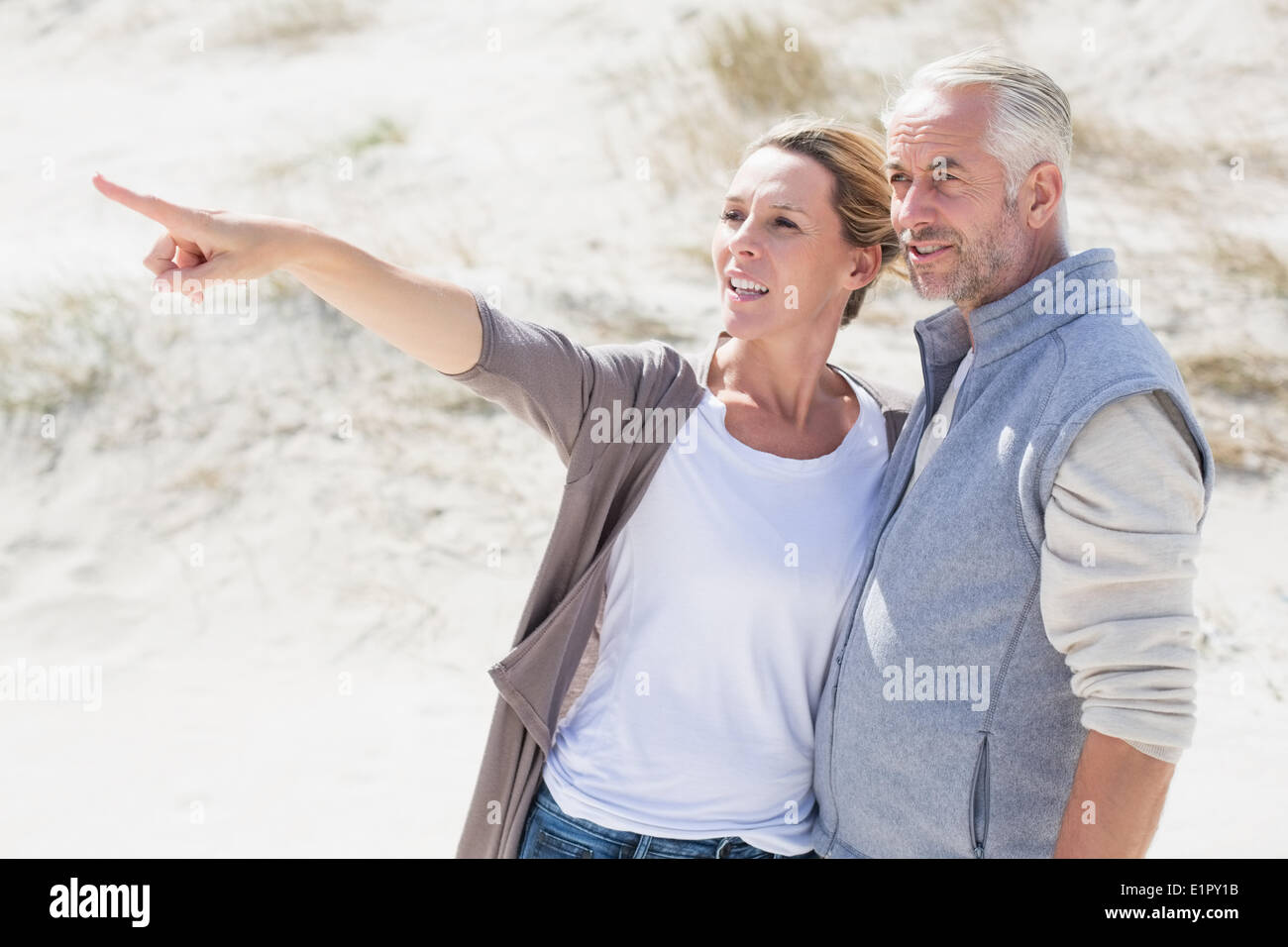 Happy couple on the beach looking at something Stock Photo