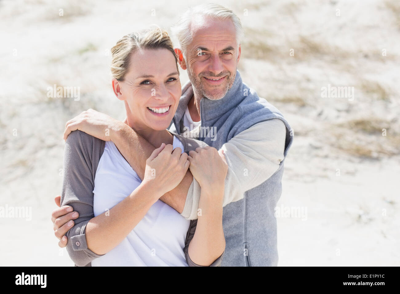 Happy hugging couple on the beach looking at camera Stock Photo