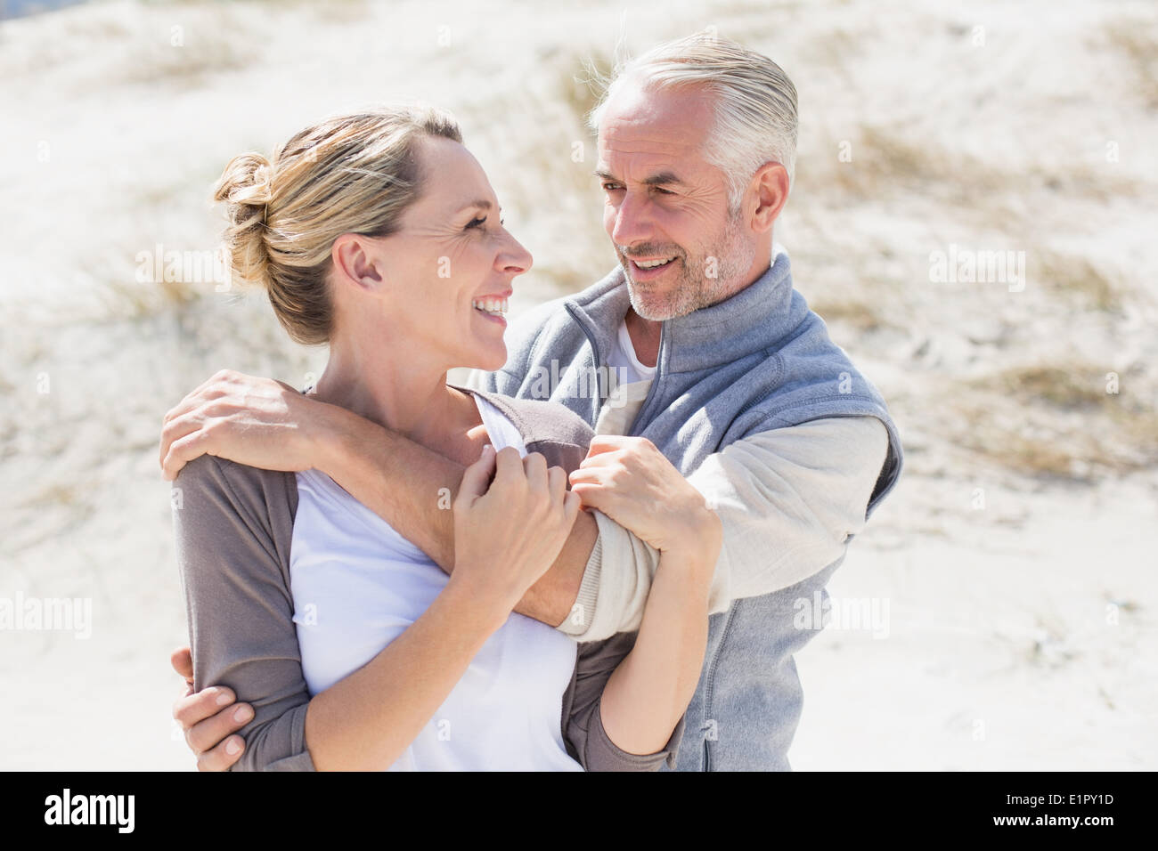 Happy hugging couple on the beach looking at each other Stock Photo
