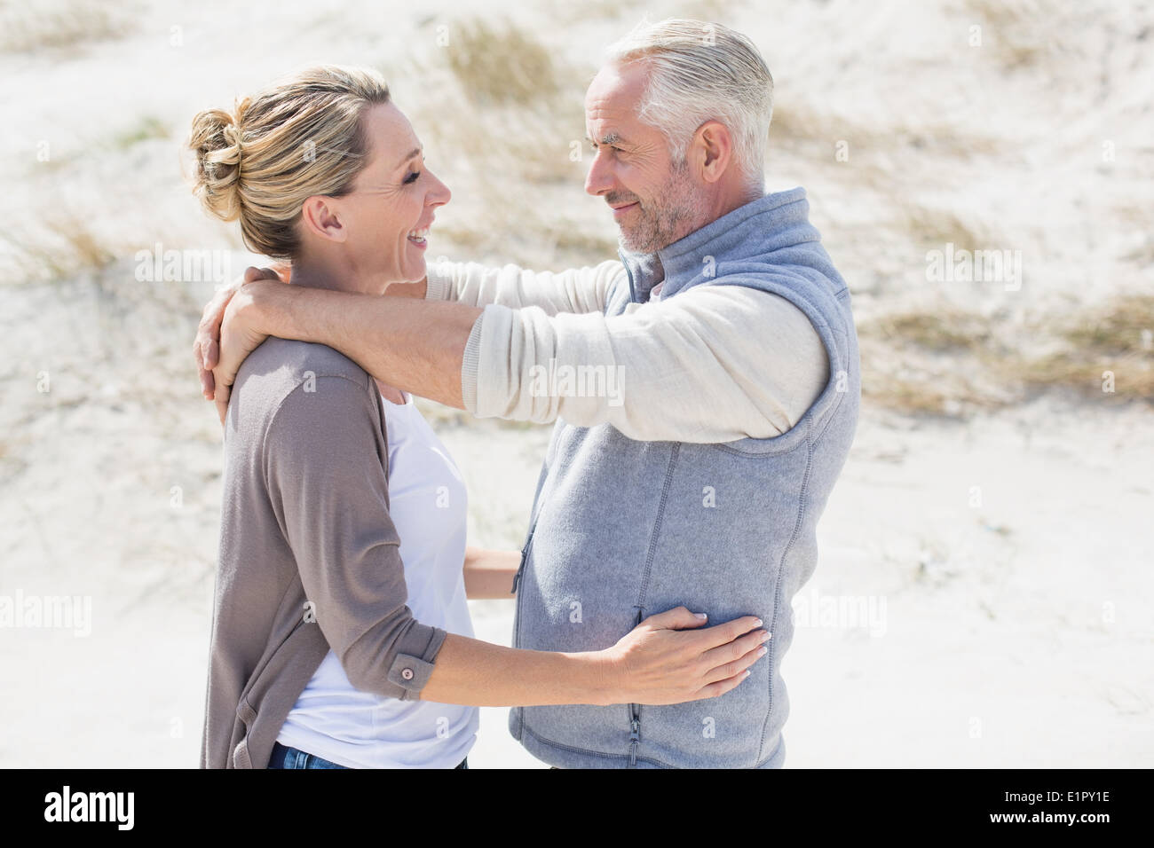 Happy hugging couple on the beach looking at each other Stock Photo