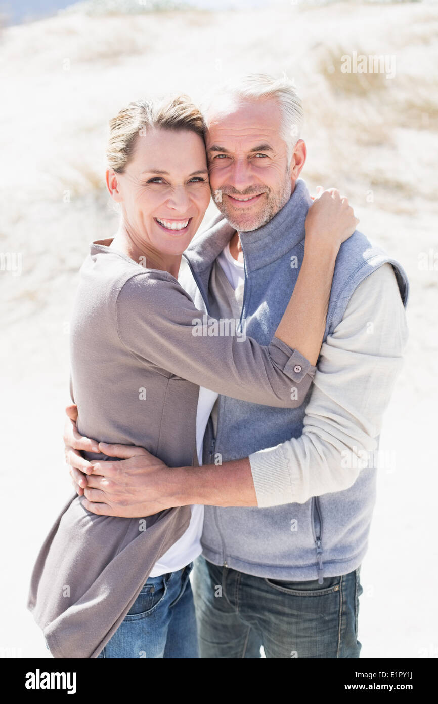 Happy hugging couple on the beach looking at camera Stock Photo