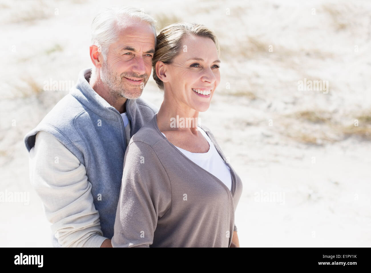 Happy hugging couple on the beach looking away Stock Photo