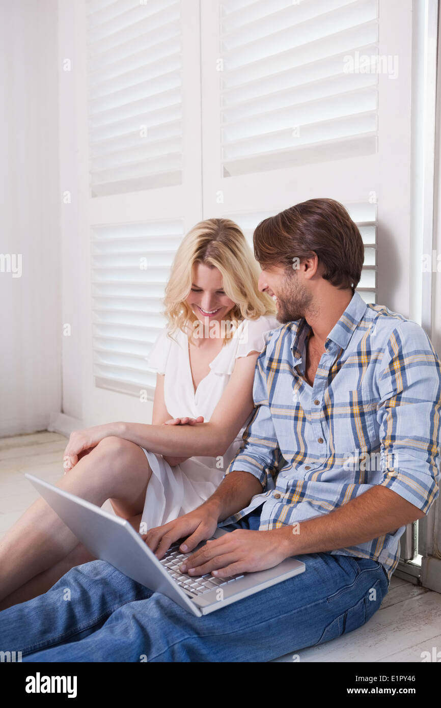 Young couple sitting on floor using laptop Stock Photo