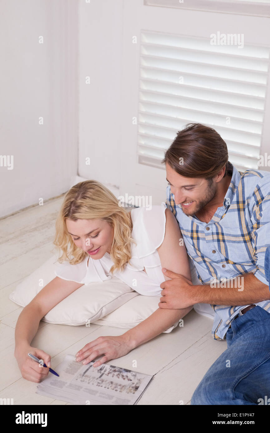 Young couple sitting on floor doing crossword Stock Photo