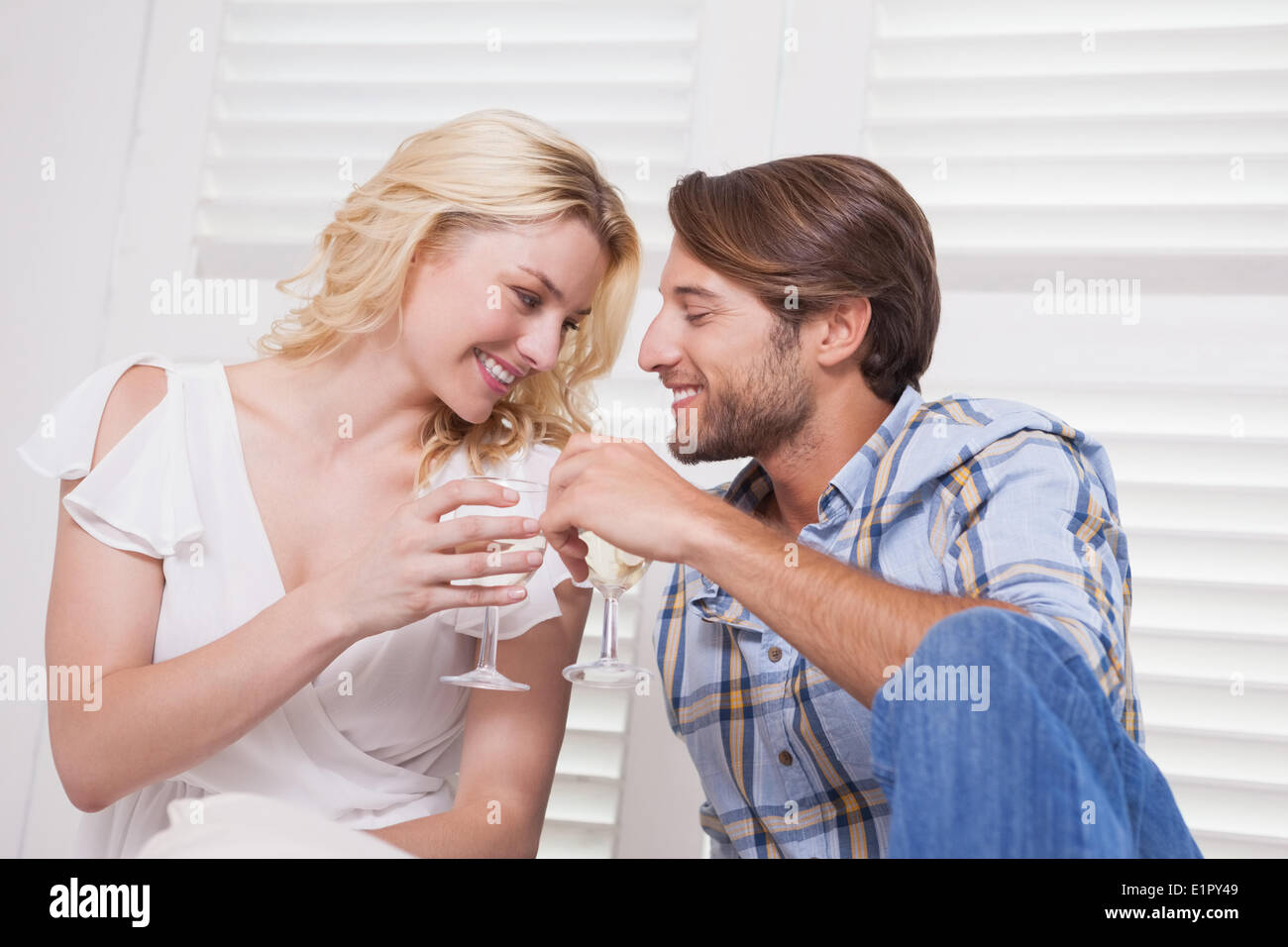 Young couple sitting on floor drinking wine Stock Photo