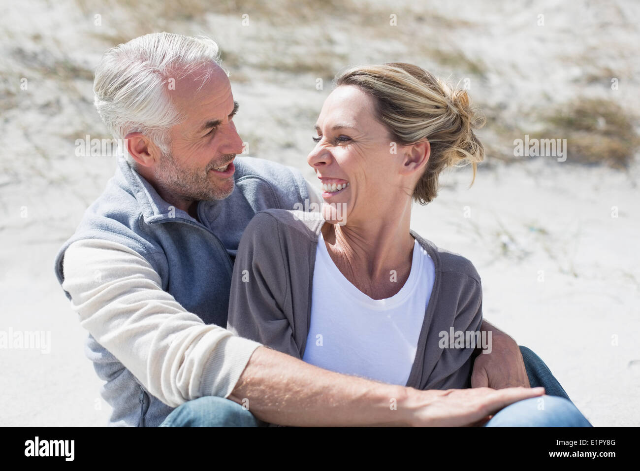 Attractive couple smiling at each other on the beach Stock Photo