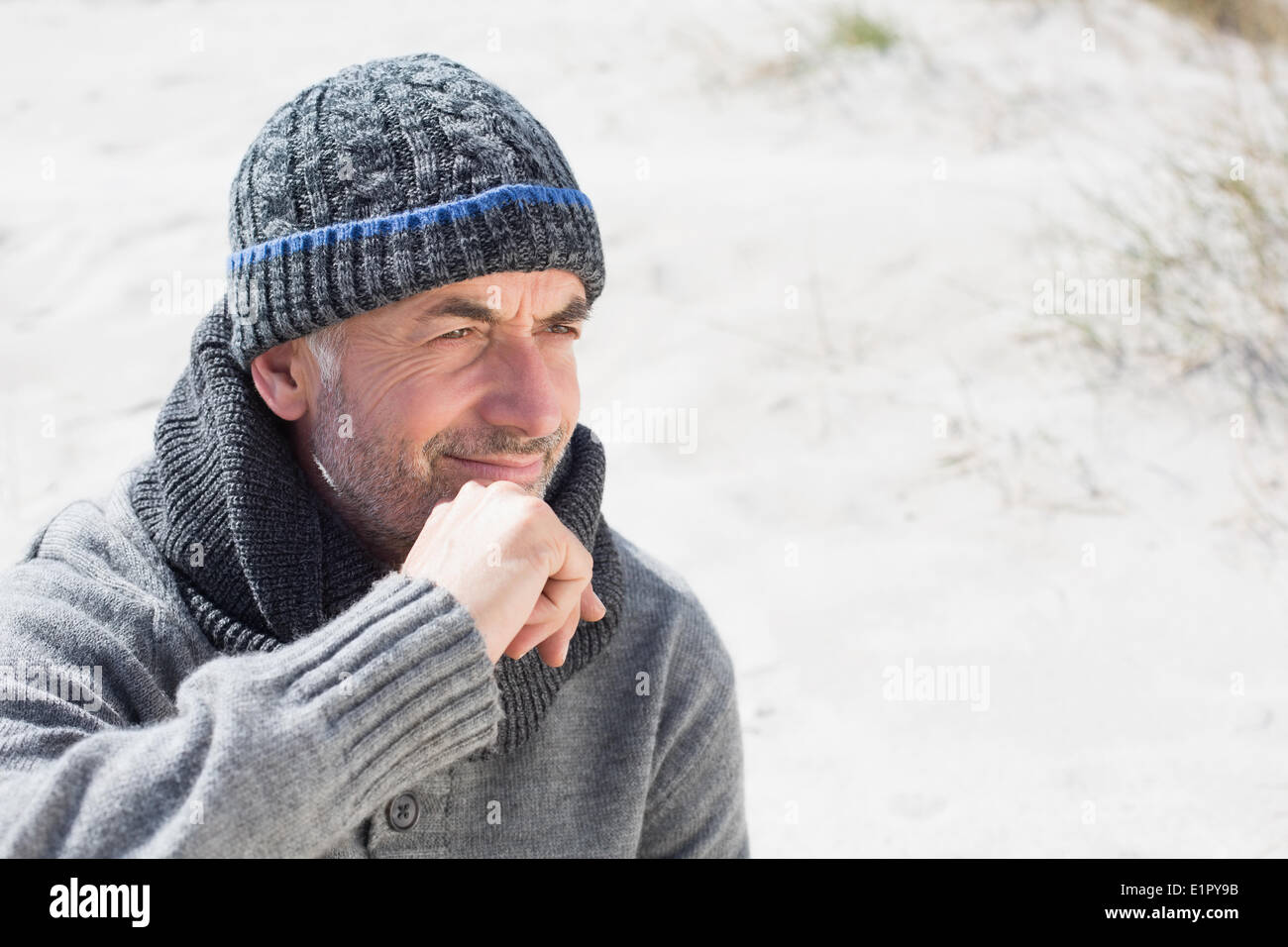 Attractive man smiling on the beach in hat and scarf Stock Photo