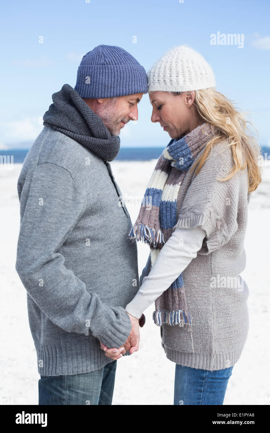 Attractive couple standing on the beach in warm clothing Stock Photo