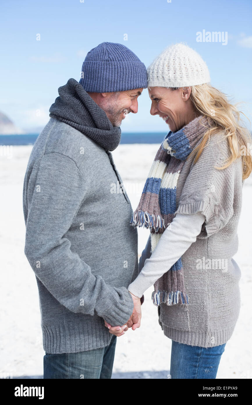 Smiling couple standing on the beach in warm clothing Stock Photo