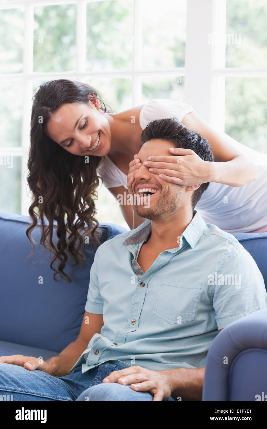Pretty brunette covering her boyfriends eyes on the couch Stock Photo