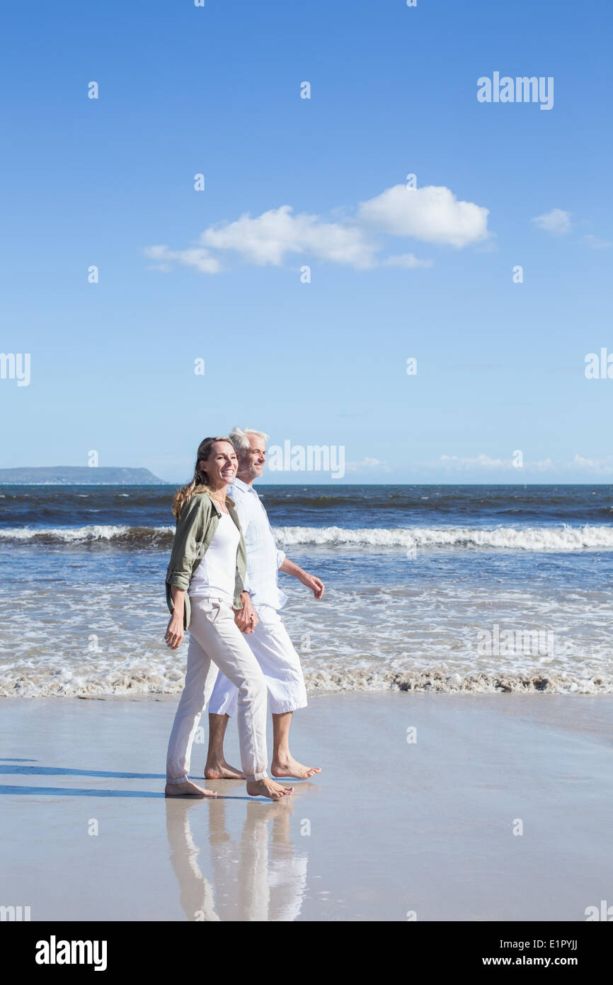 Happy couple strolling barefoot on the beach Stock Photo