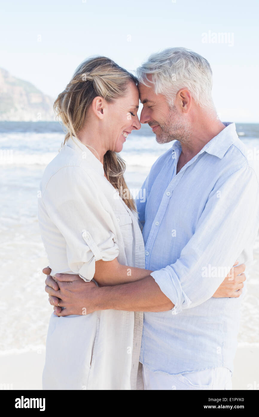Happy couple hugging on the beach looking at each other Stock Photo