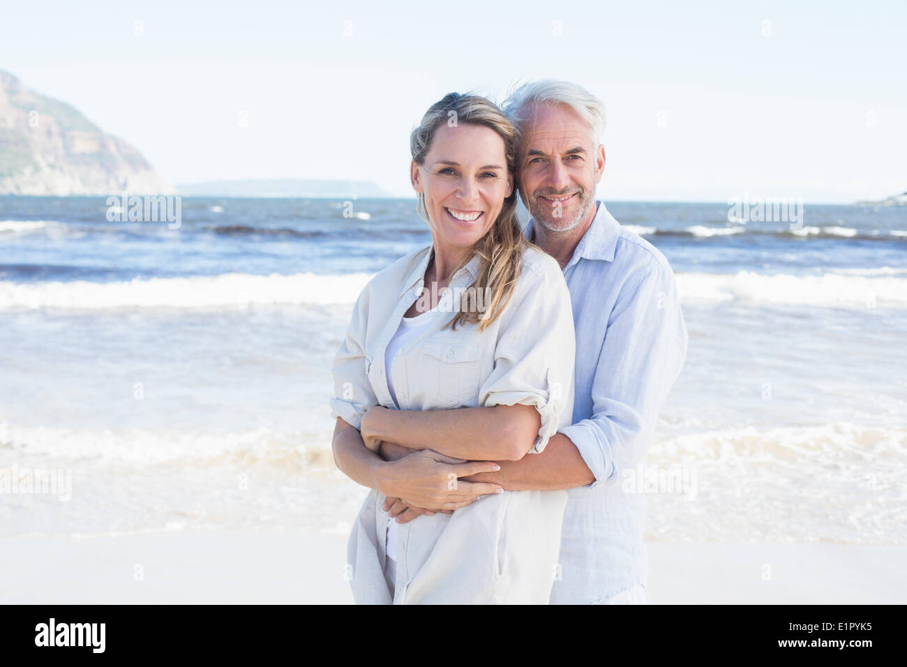 Happy couple hugging on the beach woman looking at camera Stock Photo
