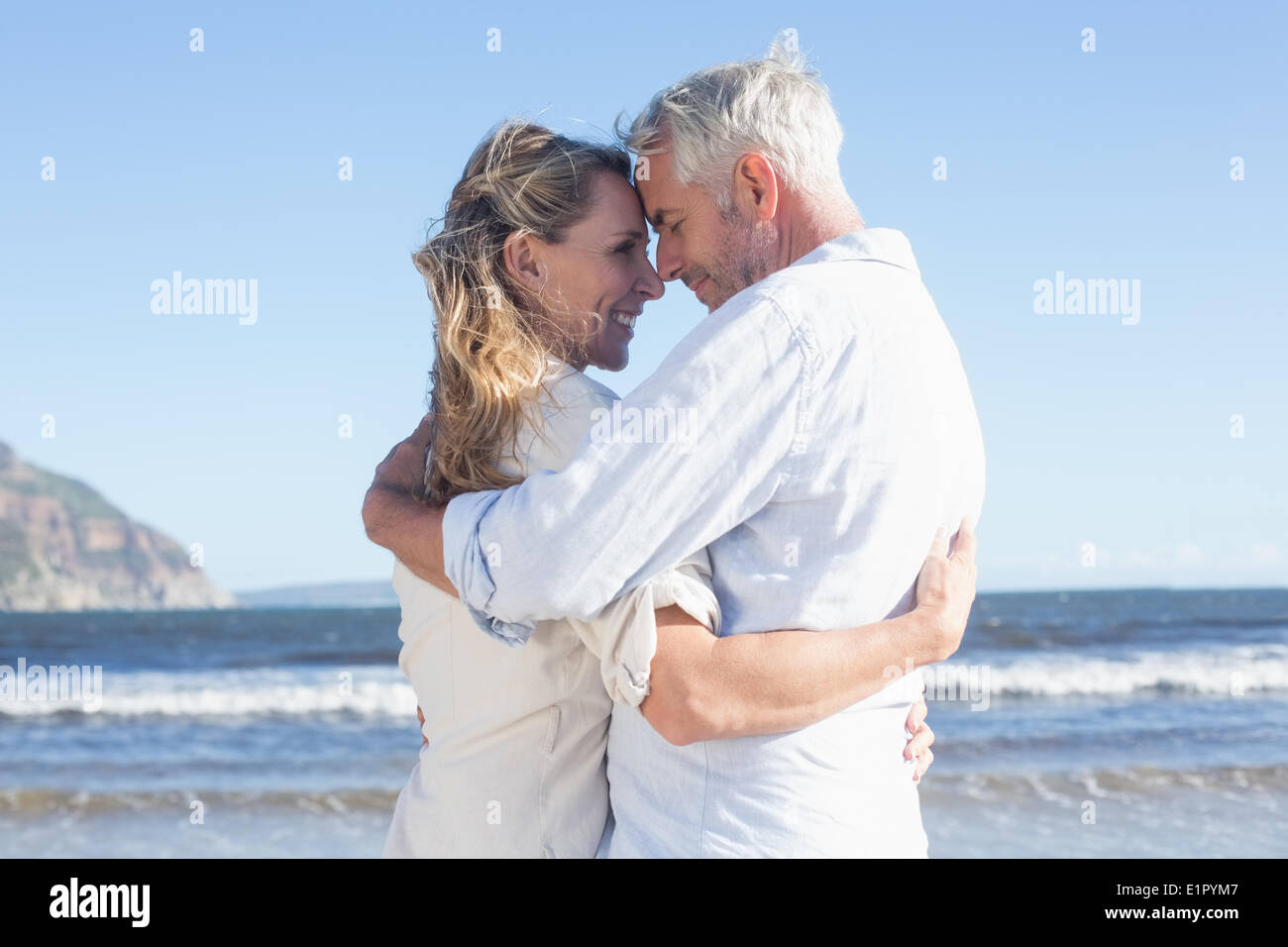 Happy couple on the beach touching faces Stock Photo