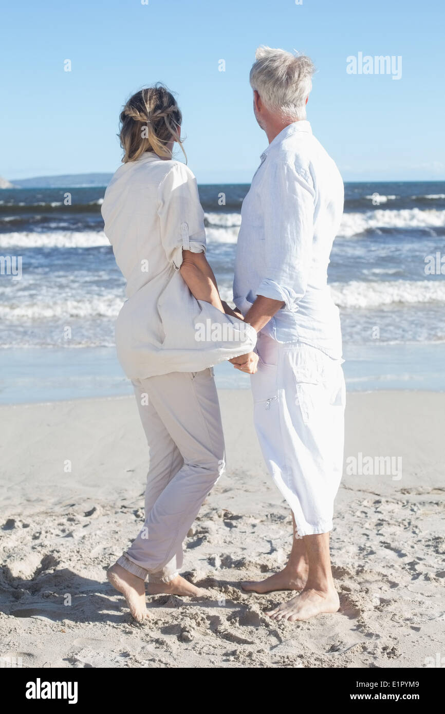 Couple on the beach looking out to sea holding hands Stock Photo - Alamy
