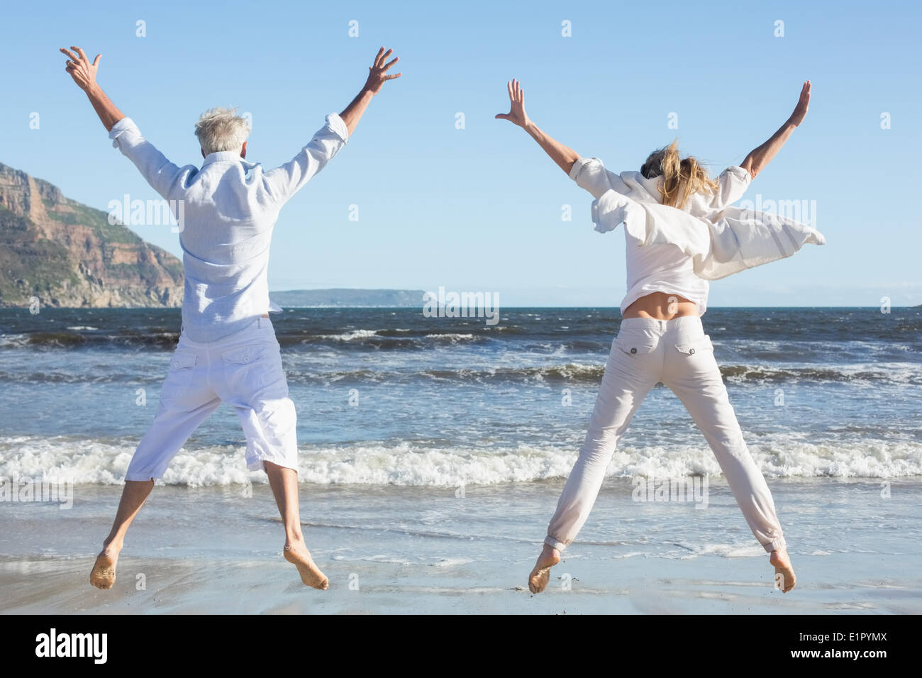 Couple jumping on the beach together Stock Photo