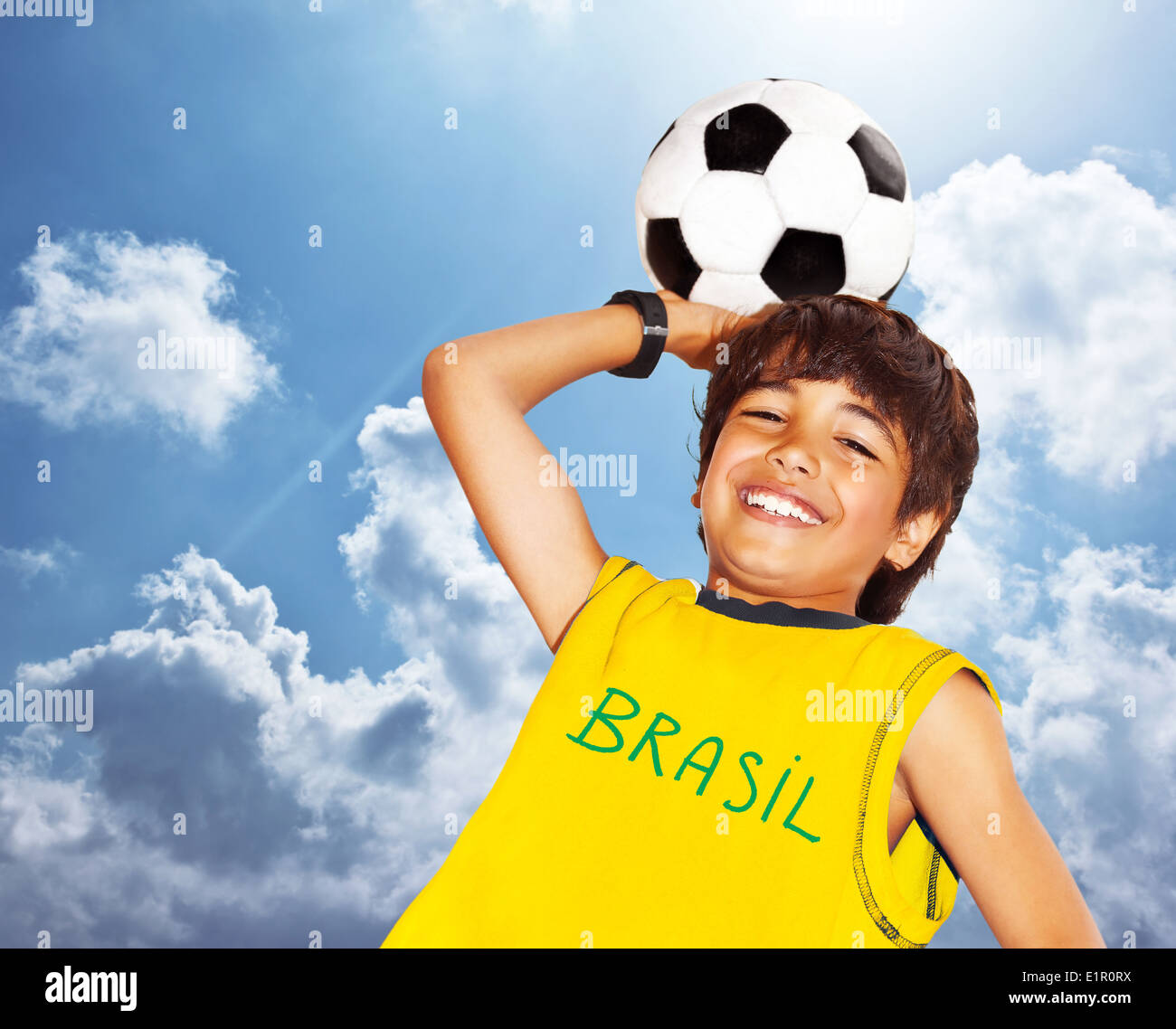 Cute boy playing football outdoor, happy child, young male teen goalkeeper enjoying sport game, holding ball Stock Photo