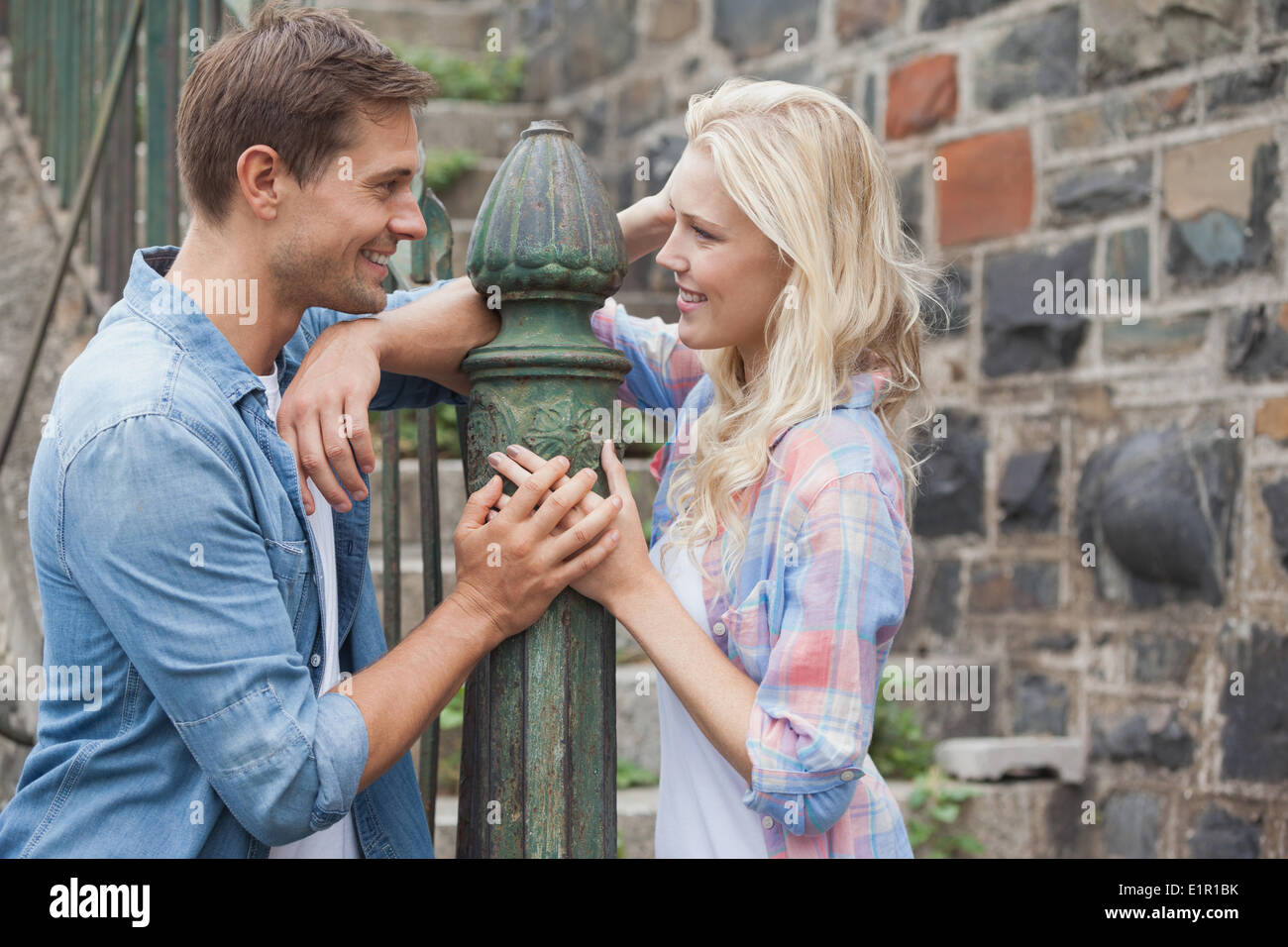 Hip young couple smiling at each other by railings Stock Photo