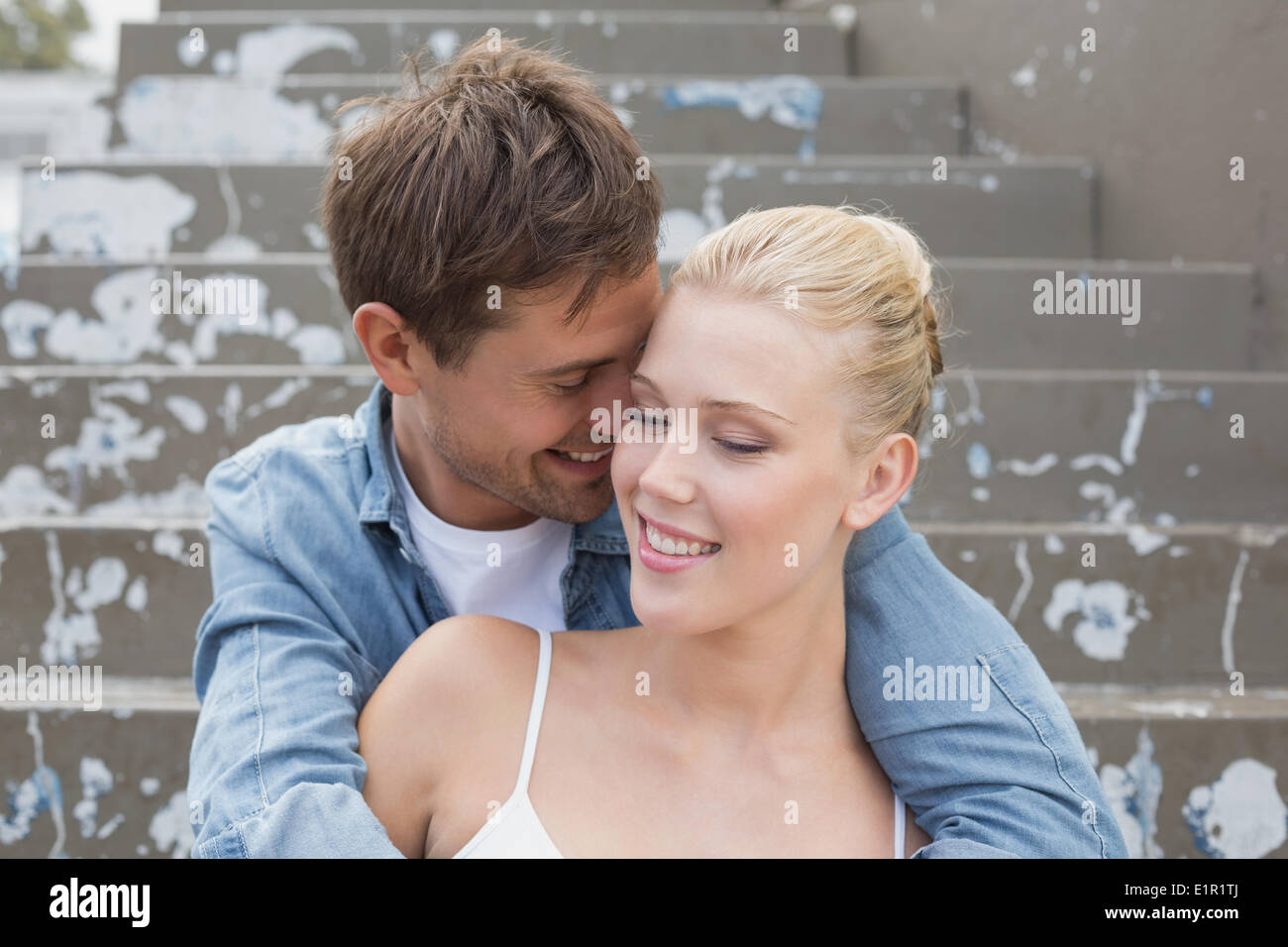 Hip young couple sitting on steps showing affection Stock Photo