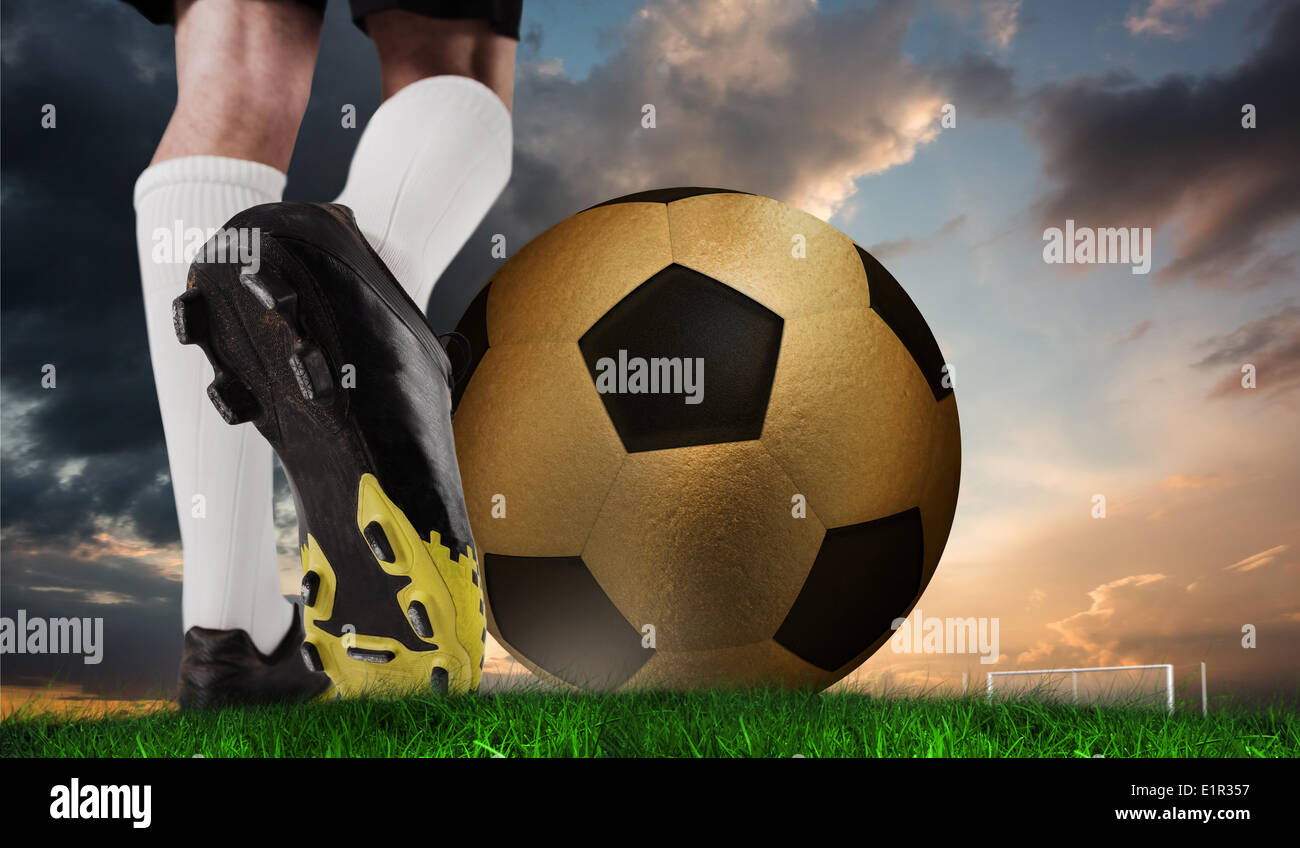 Composite image of football boot kicking huge gold ball Stock Photo