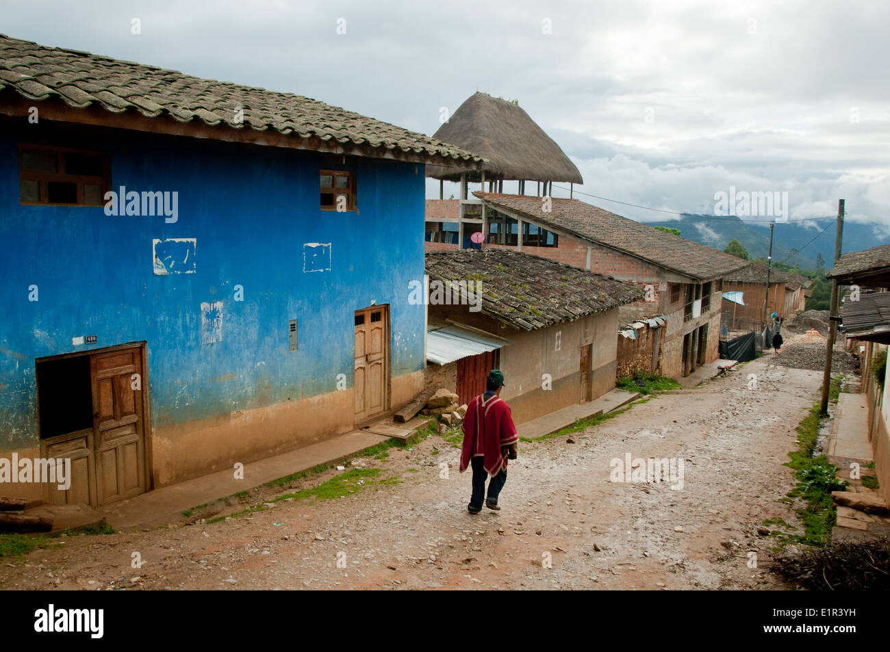 Traditionally Dressed Peruvian Man Walks Down Muddy Peruvian Street in Mountain Village Stock Photo