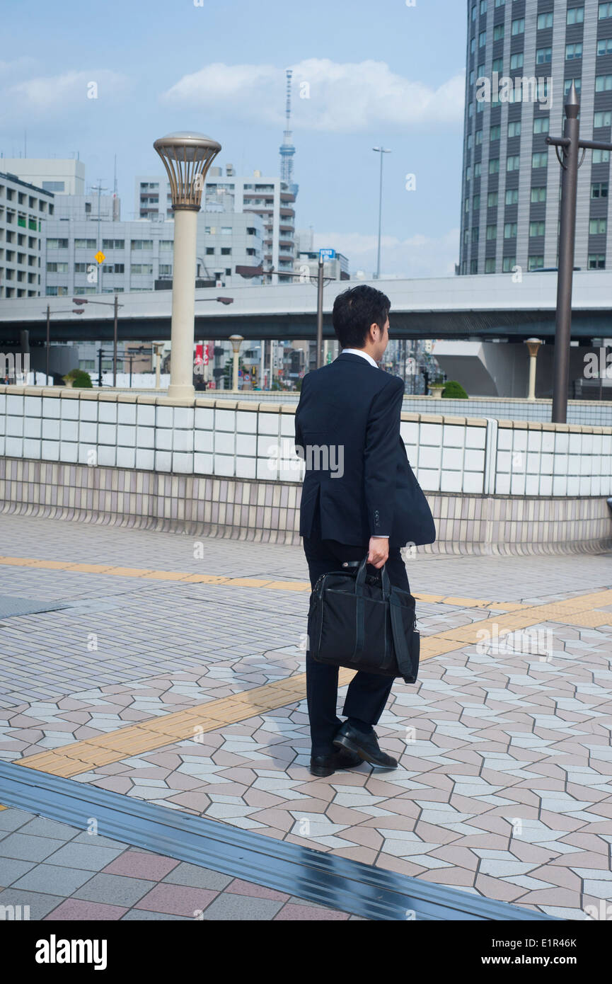 Tokyo Japan 2014  - A man wearing a black suit and holdng a suitcase in Ueno walking area Stock Photo