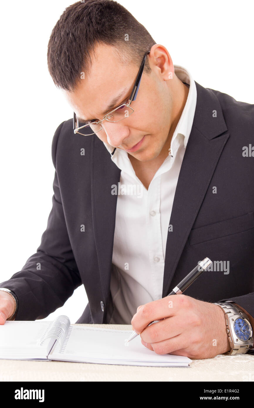 serious man in suit wearing glasses writing with pen in notebook Stock Photo