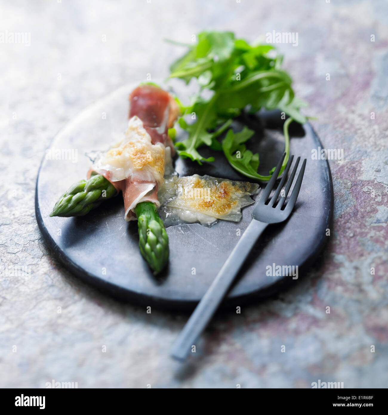 Raclette with green asparagus,raw ham and parmesan Stock Photo