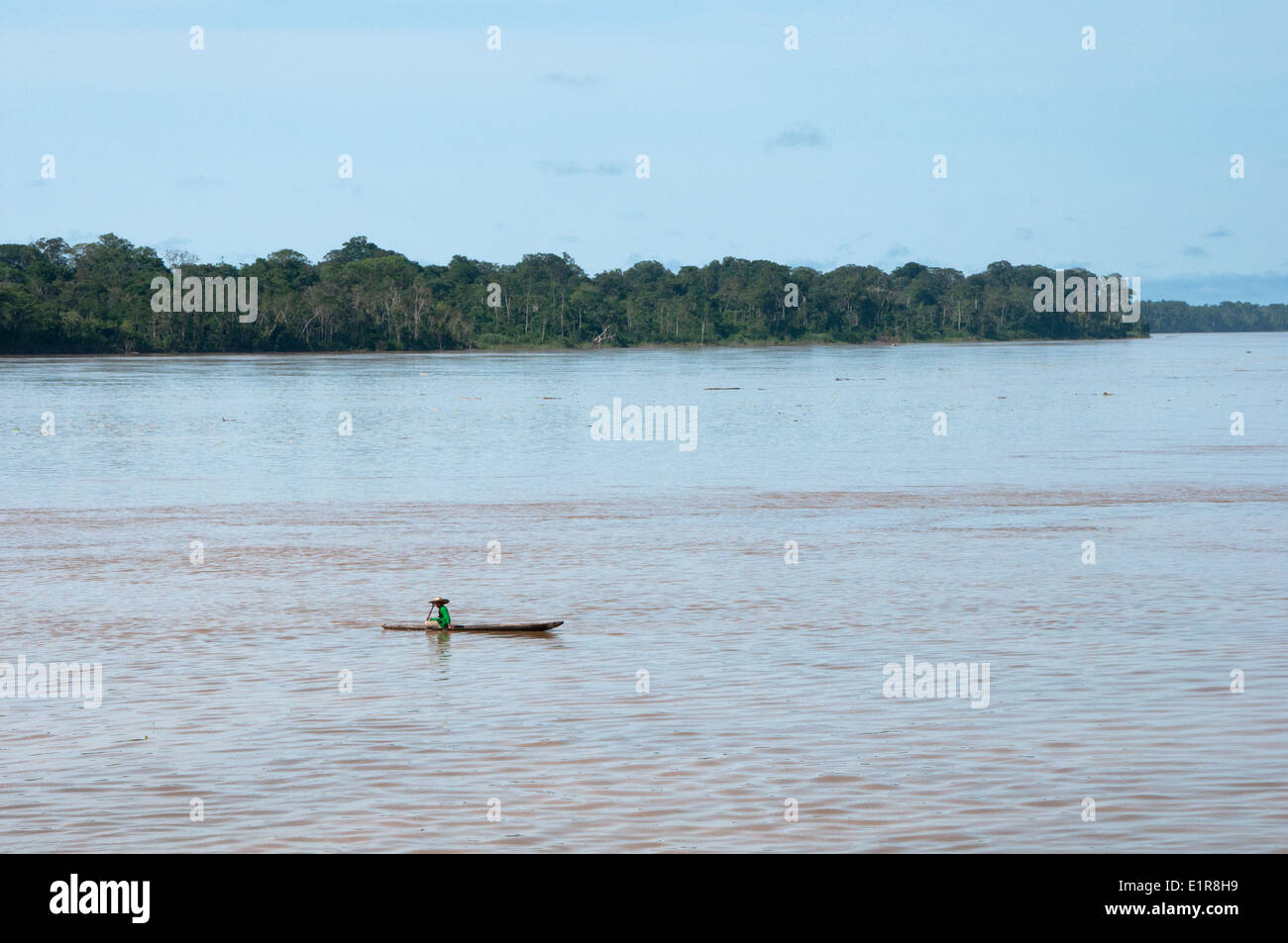 Small Dug out Canoe looks tiny on vast Peruvian Amazon River Stock Photo
